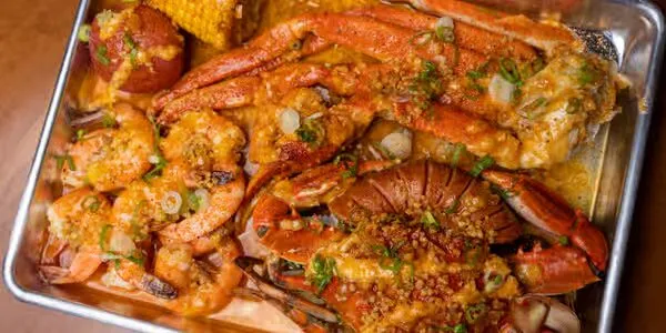A loaded seafood boil at Boiling Dragon with crab, shrimp, corn, sausage, and potatoes