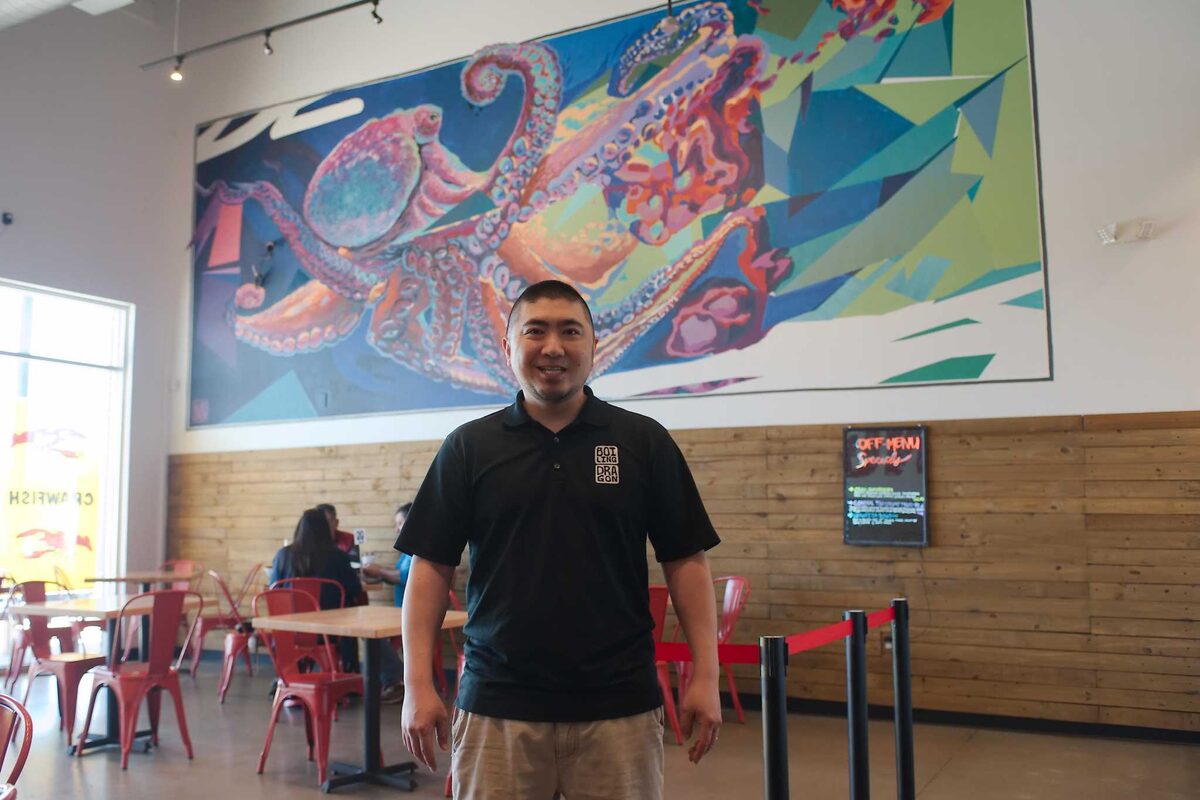Harold Wong, owner of Boiling Dragon, beside the restaurant's murals